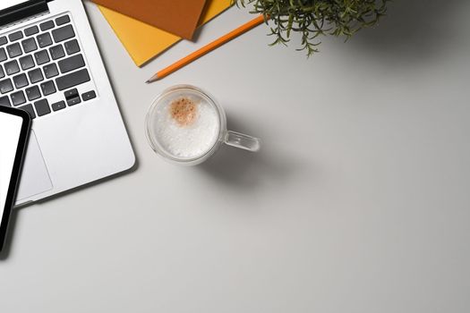 Top view computer laptop, coffee cup and notebook on simple workspace.