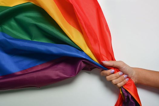 Woman holding colorful rainbow flag on white background. LGBT concept.