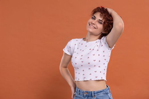 Attractive young girl with a beautiful smile one hundred and one brick-colored background. White blouse with cherry pattern.