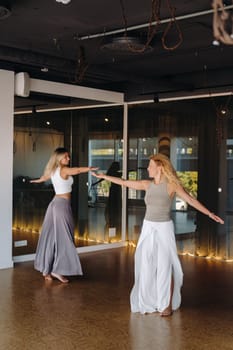 Two women in sportswear are doing dance yoga in the gym.