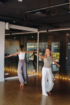 Two women in sportswear are doing dance yoga in the gym.