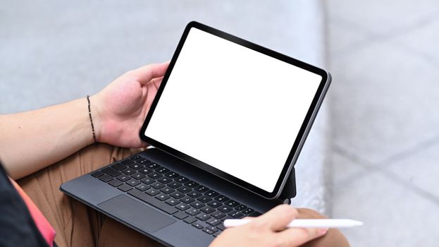 Young man holding stylus pen and using digital tablet at outdoor.