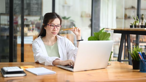 Asian woman sitting in coffee shop and using laptop computer.