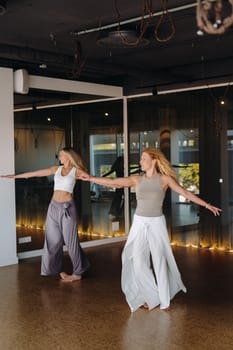 Two women in sportswear are doing dance yoga in the gym.