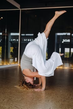 A woman Performing yoga exercises on her head in the gym.