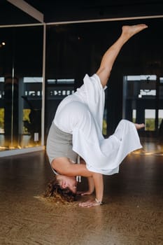 A woman Performing yoga exercises on her head in the gym.