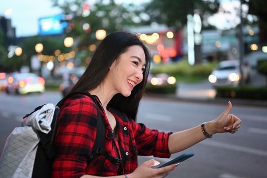 Smiling Asian woman using application of taxi service app on smart phone.