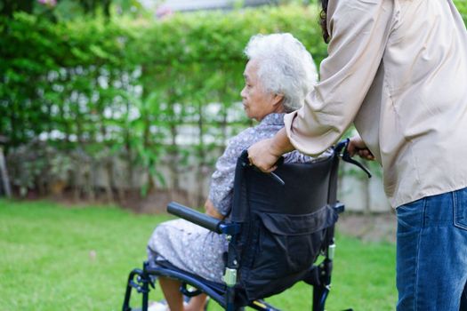 Caregiver help Asian elderly woman disability patient sitting on wheelchair in park, medical concept.