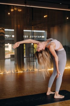 The girl does yoga. A woman in sports clothes does yoga exercises in the gym.