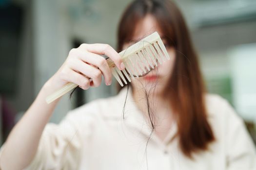 Asian woman have problem with long hair loss attach to comb brush.