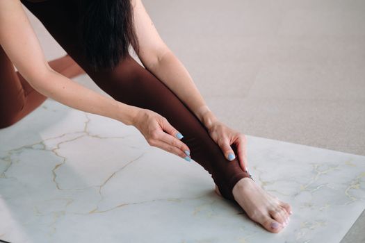 close-up of the legs and arms of a girl who does yoga in a fitness room. Healthy lifestyle, fitness, training, self-care.