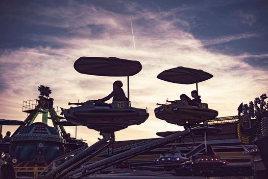 Rovigo, Italy 25 October 2022: Carousel fairground plane at sunset silhouette