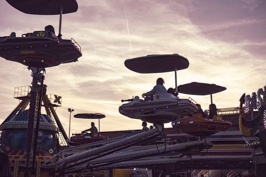 Rovigo, Italy 25 October 2022: Carousel fairground plane at sunset silhouette