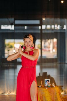 A girl in a red dress moves in a dance meditating indoors . Dynamic dance,
