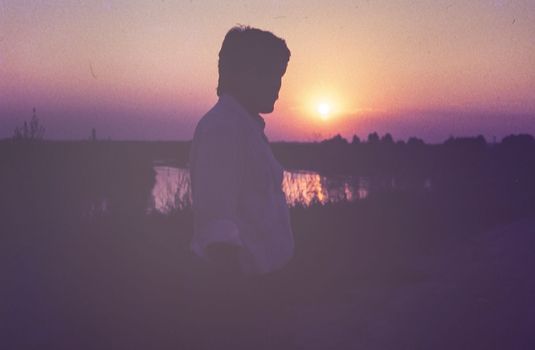 Rovigo, Italy october 1976: Man silhouette sunset countryside scene in 70s