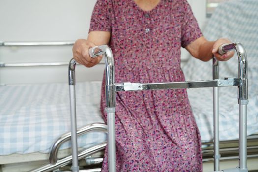 Asian elderly woman disability patient walk with walker in nursing hospital, medical concept.