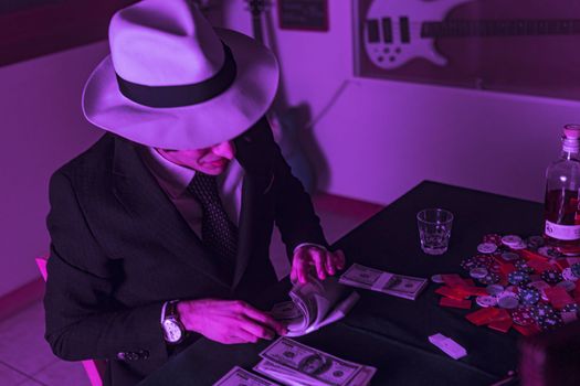 Man's hands carefully puts stacks of dollars into a black briefcase, preparing for a poker game. His bankroll is neatly arranged and organized, ready for the challenge ahead.