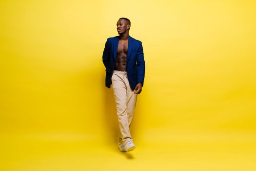 Guy in blue suit on a yellow background. Handsome athletic man in jacket smiling