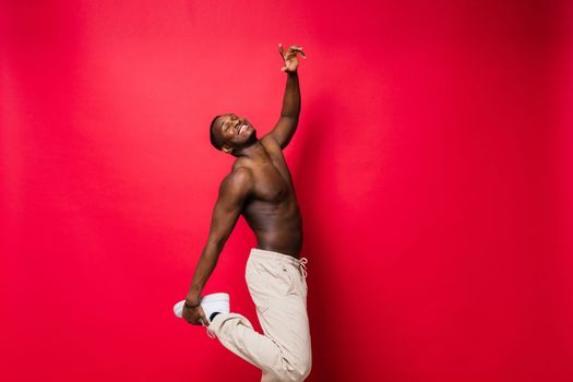 Young handsome african man topless portrait in studio on red background