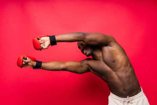 Muscular serious looking african boxer training, in studio red background