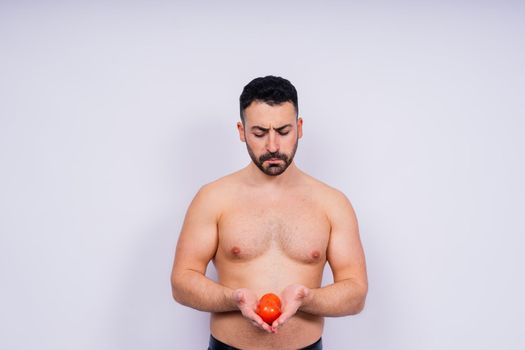 Full isolated studio picture from a young naked man with underwear and tomatoes
