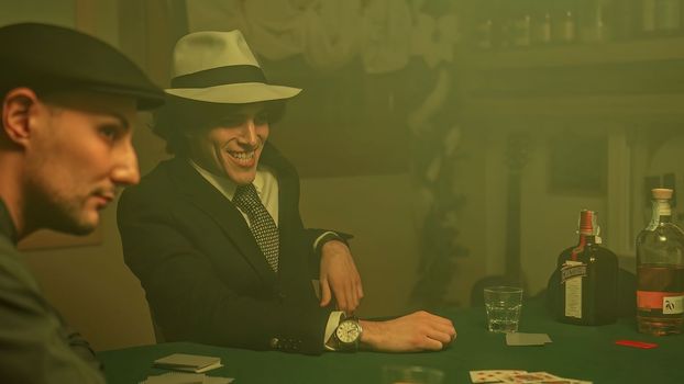 A poker player sits at a dimly lit table, staring down at their cards with a defeated expression. Disappointment and defeat associated with gambling.
