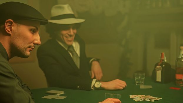 A poker player sits at a dimly lit table, staring down at their cards with a defeated expression. Disappointment and defeat associated with gambling.