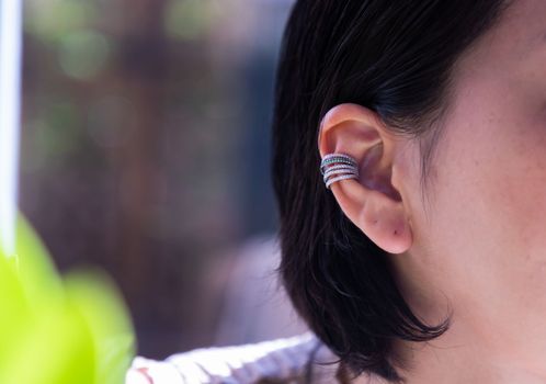 Detail of young woman wearing beautiful silver earring. Women accessories. Selective focus.