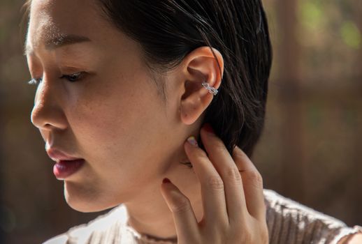 Detail of young woman wearing beautiful silver earring. Women accessories. Selective focus.