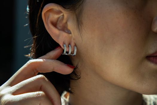 Detail of young woman wearing beautiful silver earring. Women accessories. Selective focus.