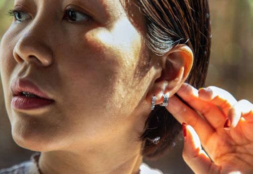 Detail of young woman wearing beautiful silver earring. Women accessories. Selective focus.