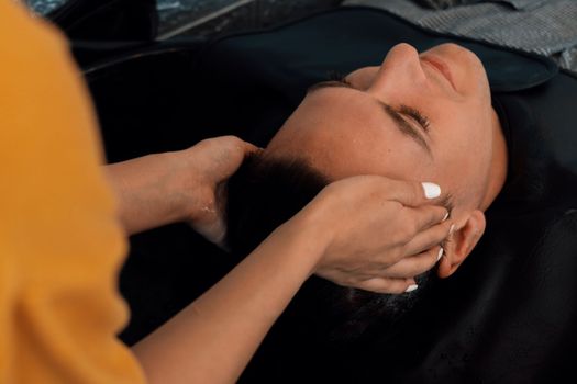 Closeup caucasian man getting hair wash by professional hairdresser with shampoo feels relax and comfortable . Qualified hairdresser with her barbershop, salon providing haircare concept.