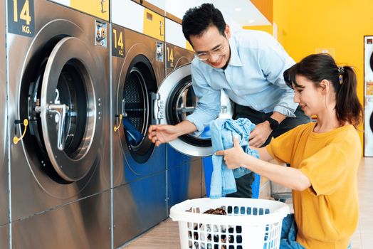 Asian people using qualified coin operated laundry machine in the public room to wash their cloths. Concept of a self service commercial laundry and drying machine in a public room.