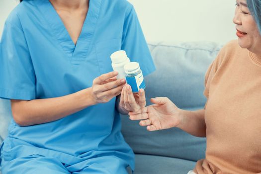 Caregiver advising contented senior woman on medication in the living room. Medication for seniors, nursing house, healthcare at home.