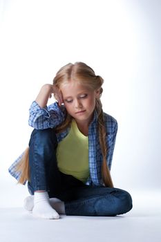 Studio portrait of beautiful blonde girl sit on floor