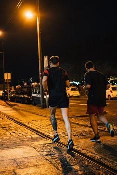 Men runners training in oporto city at night.