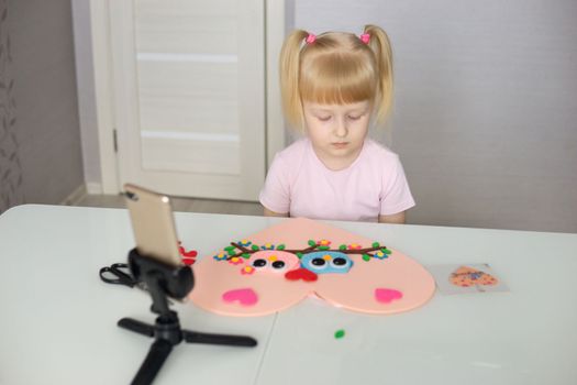 A blogger girl makes a felt craft for Valentine's Day in the shape of a heart. The concept of children's creativity and handmade