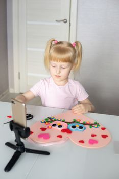 A blogger girl makes a felt craft for Valentine's Day in the shape of a heart. The concept of children's creativity and handmade