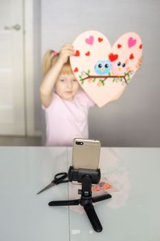 A blogger girl makes a felt craft for Valentine's Day in the shape of a heart. The concept of children's creativity and handmade
