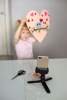 A blogger girl makes a felt craft for Valentine's Day in the shape of a heart. The concept of children's creativity and handmade