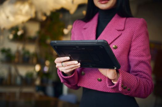 Cropped view with focus on electronic gadget. Successful businesswoman, executive director of restaurant, using modern digital tablet for work, taking notes and writing weekly report. Business People