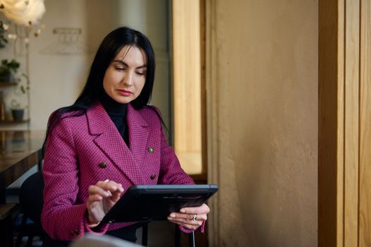 Confident successful Caucasian middle-aged woman, a goal-oriented business person, CEO, successful restaurateur using a digital tablet for work in newly opened restaurant. People and Business concept