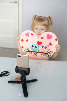 A blogger girl makes a felt craft for Valentine's Day in the shape of a heart. The concept of children's creativity and handmade