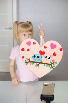 A blogger girl makes a felt craft for Valentine's Day in the shape of a heart. The concept of children's creativity and handmade