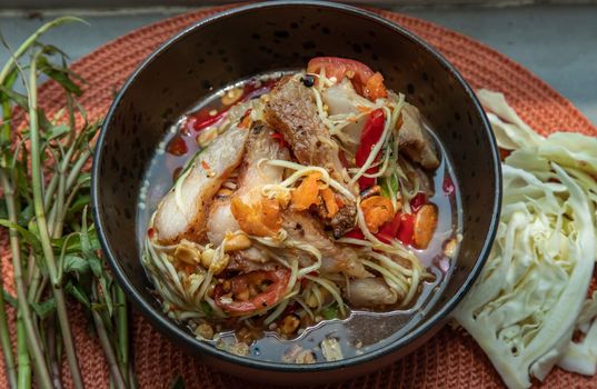 Thai papaya spicy salad (som tum) mix grilled pork neck on ceramic dishes. delicious spicy Thai food, Selective focus.