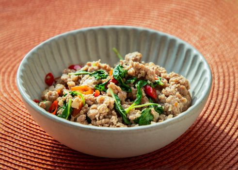 Stir-fried Thai basil with Minced pork (Pad ka prao moo) on white bowl. Popular traditional food of Thailand, Selective focus.