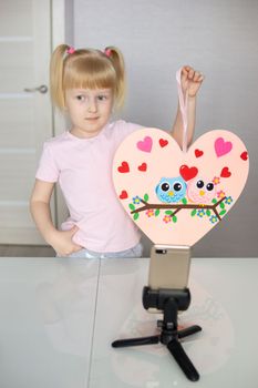 A blogger girl makes a felt craft for Valentine's Day in the shape of a heart. The concept of children's creativity and handmade