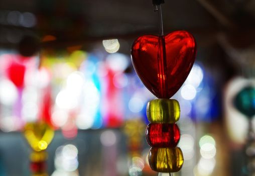 Red translucent heart on a string with a colorful bokeh background