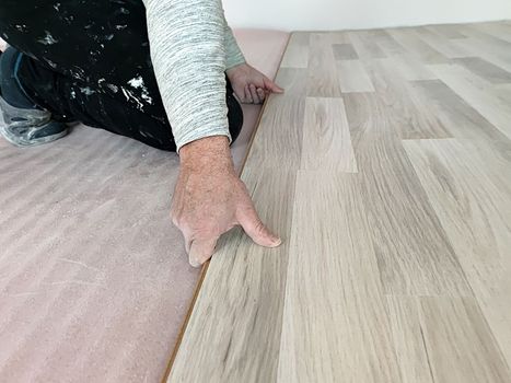 worker laying laminate on the floor close up