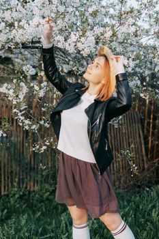 Portrait of a woman in a straw hat in a cherry blossom. Free outdoor recreation, spring blooming garden.
